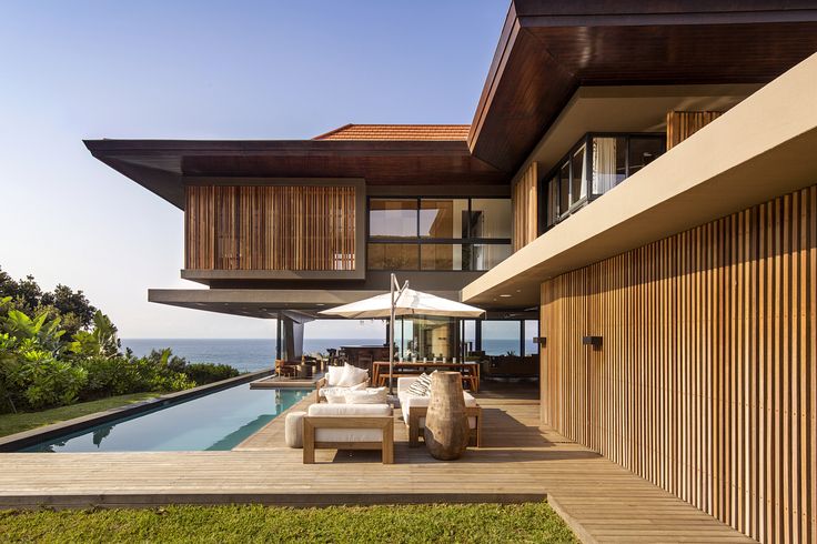 Modern tropical villa with pool and wooden slats on a sunny day in Koh Samui.