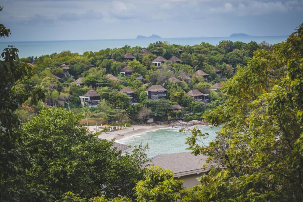 An eco-friendly villa in Koh Samui, surrounded by lush greenery, featuring sustainable materials like bamboo and solar panels.